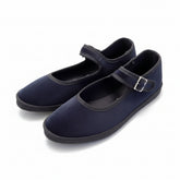 A pair suede Mary Jane shoes with hook-and-loop straps, resting on a polished stone tile floor.