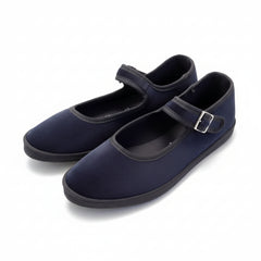 A pair suede Mary Jane shoes with hook-and-loop straps, resting on a polished stone tile floor.
