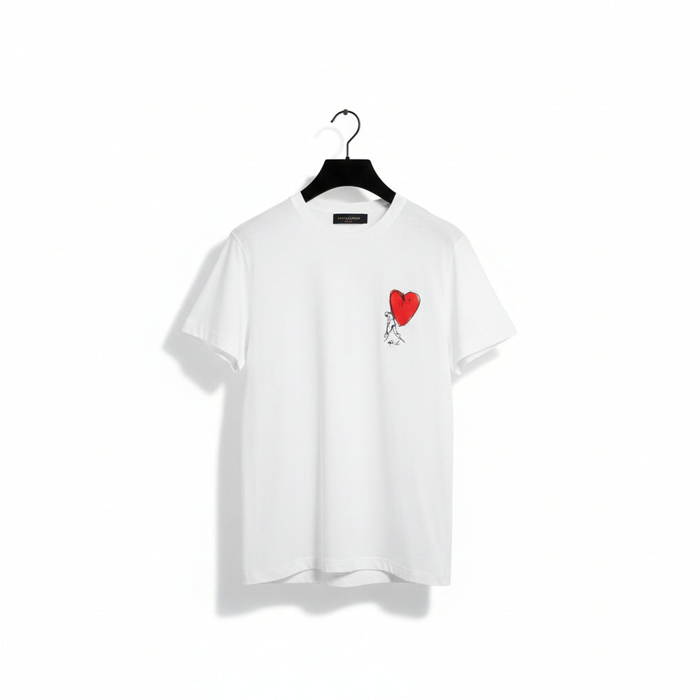 A white short-sleeve crewneck T-shirt hanging on a black hanger, featuring a small graphic on the left chest of a red heart with a black-and-white sketch figure inside it.