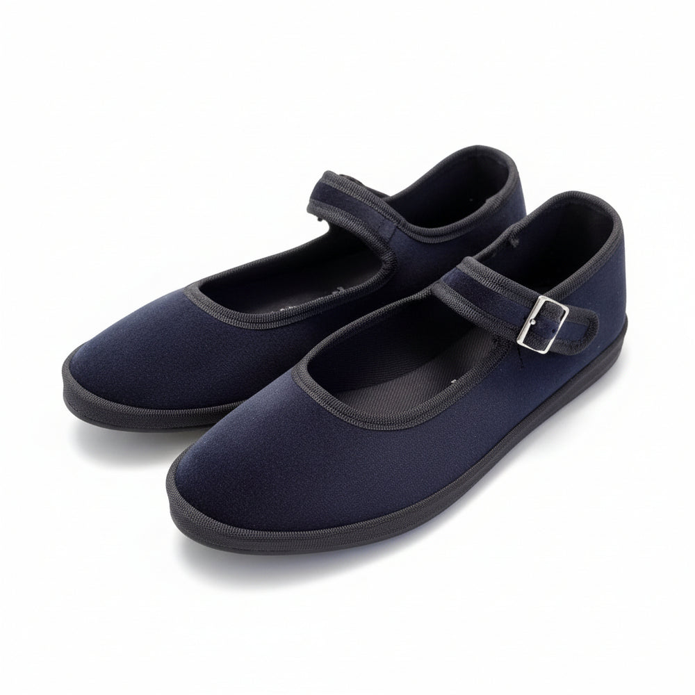 A pair suede Mary Jane shoes with hook-and-loop straps, resting on a polished stone tile floor.