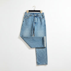 Light wash blue denim jeans laid flat on a brown marble-patterned floor, hanging from a black hanger.